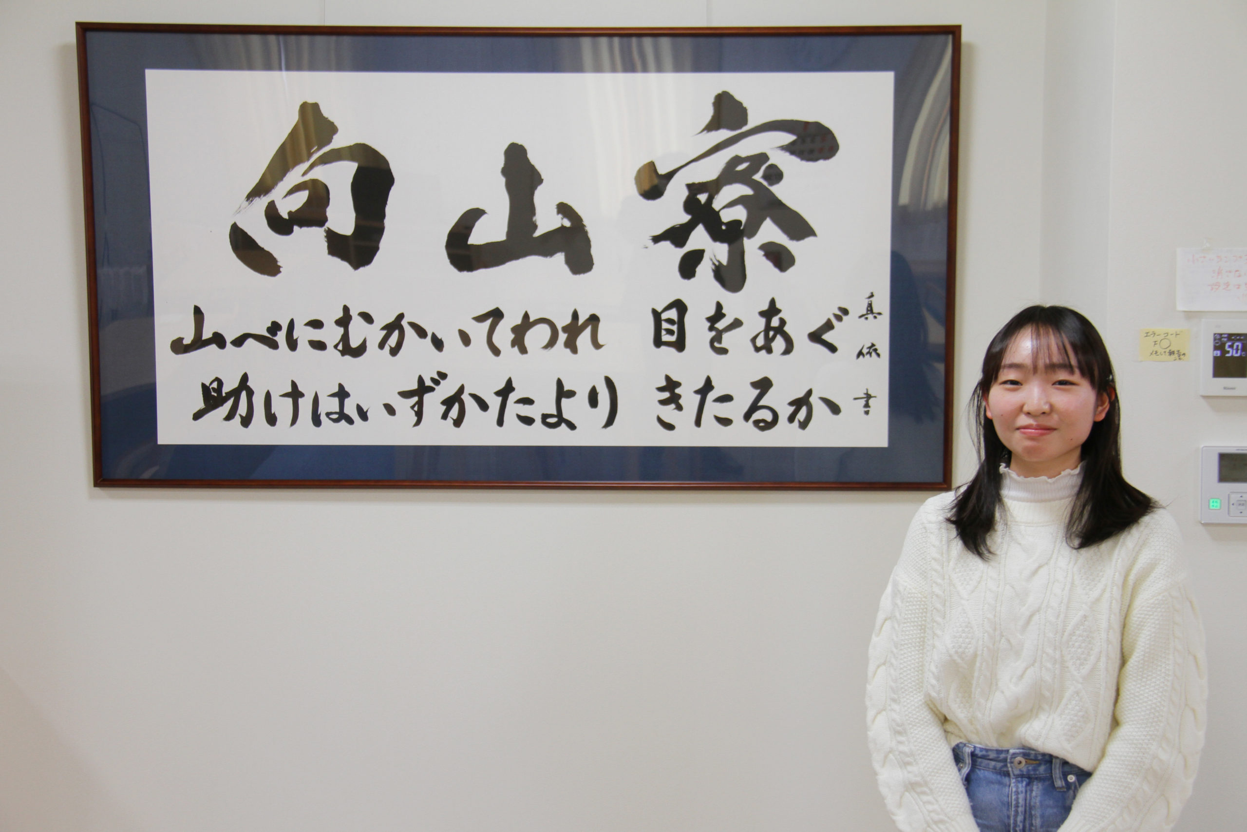 「向山寮」の掛軸と揮毫した金子真依さん