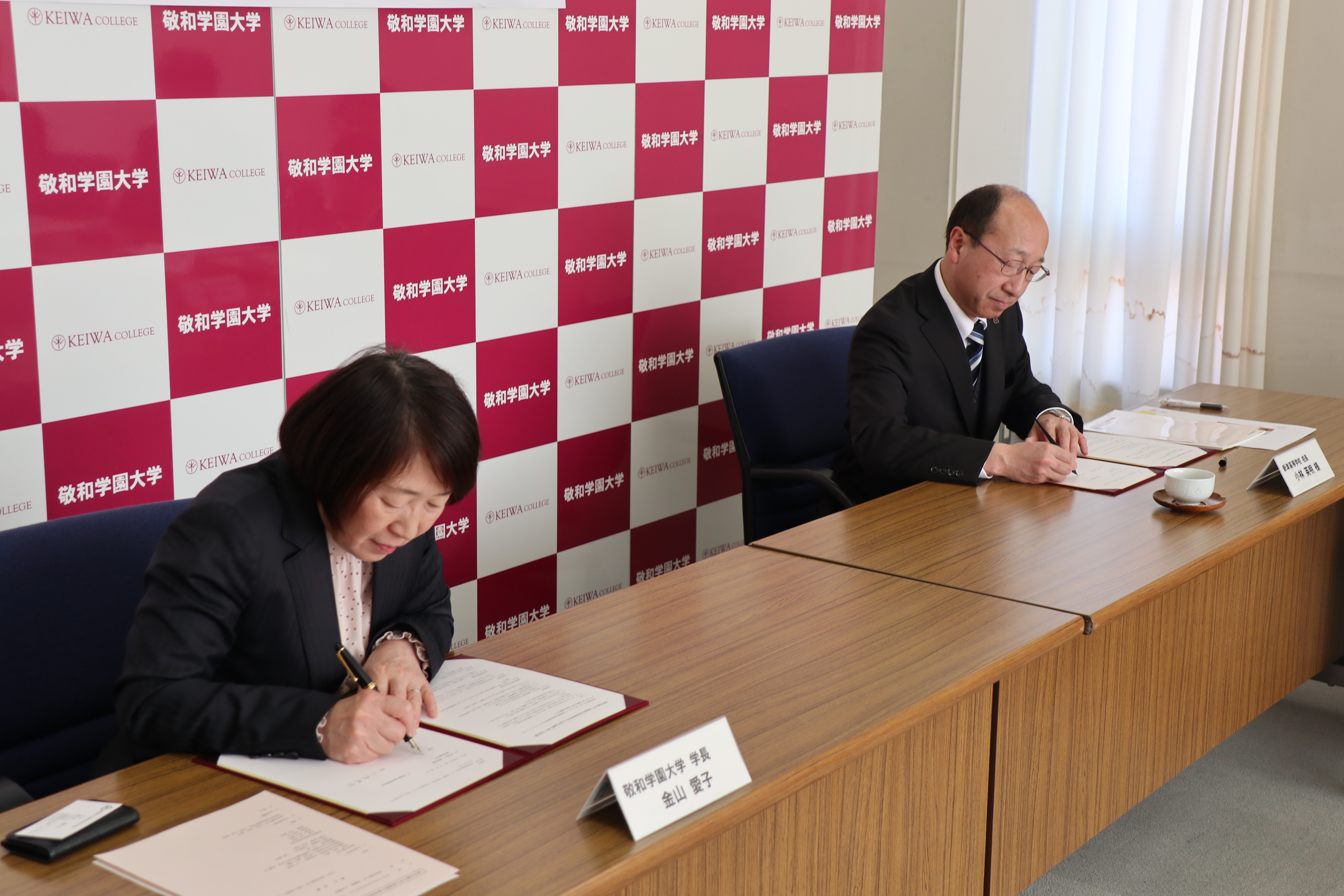 協定書にサインする金山愛子学長と小林英明学校長